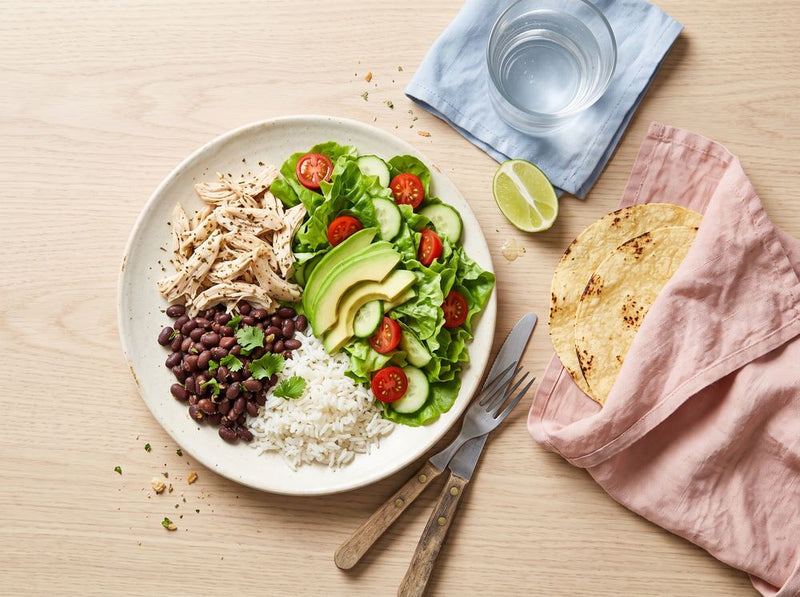 Plato con ensalada, pollo deshebrado, frijoles negros y arroz